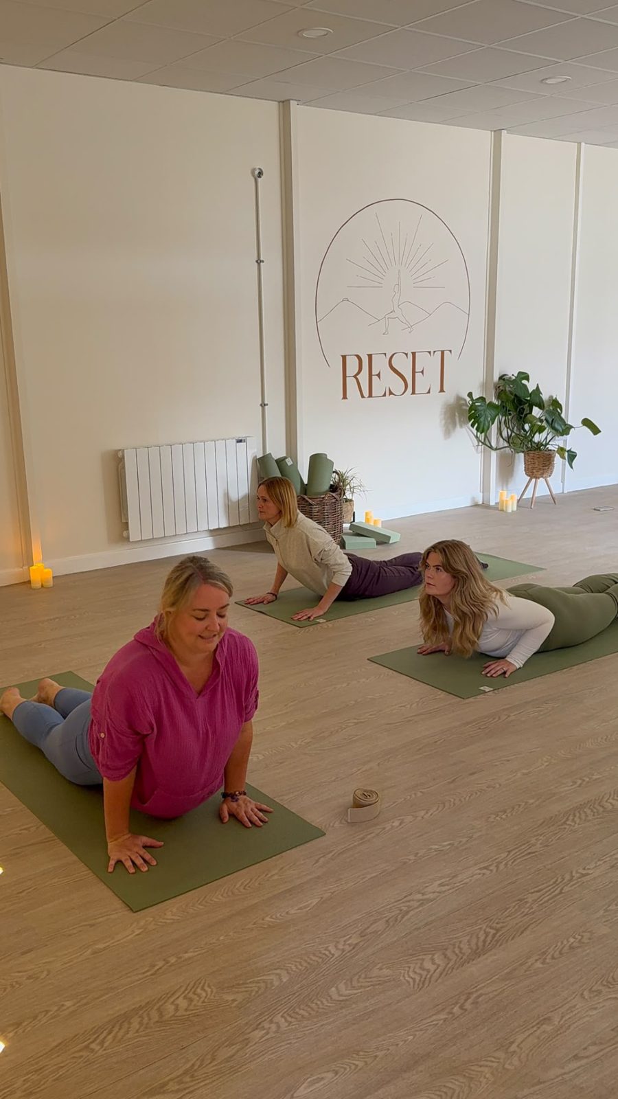Members enjoying a gentle stretch class in front of the RESET Ruthin logo wall
